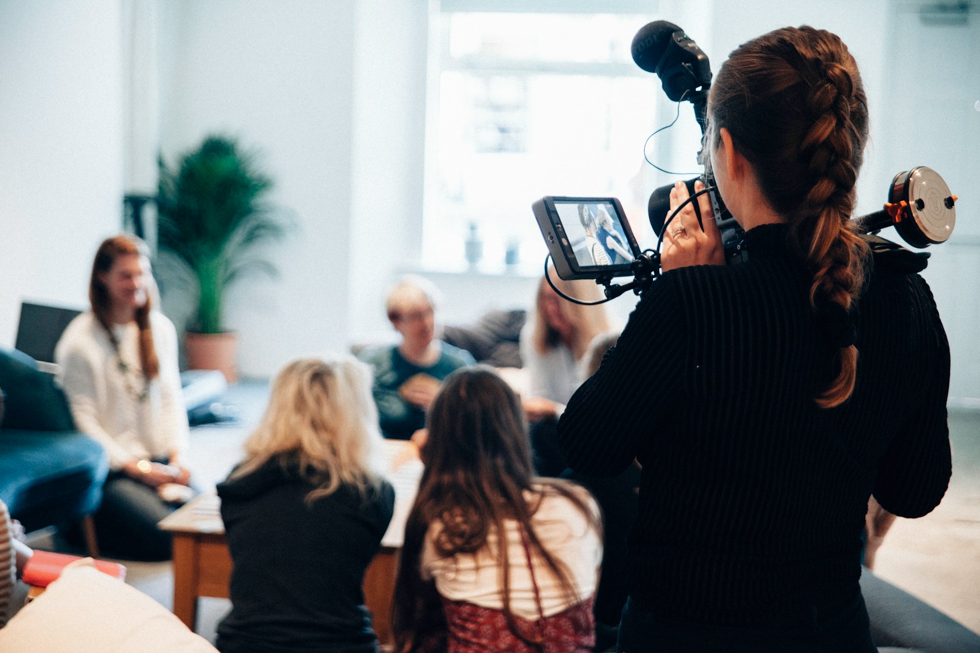 A camera operator filming a group in conversation